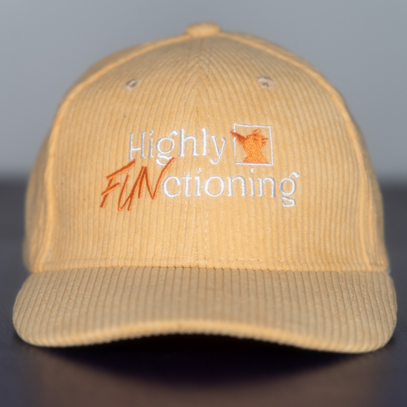 A creamy yellow colored corduroy baseball cap with 'Highly FUNctioning' and a kangaroo embroidered in white and orange on the front.