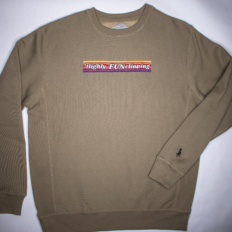 An olive green crew neck sweatshirt with the phrase 'Highly FUNCTIONING' embroidered on the chest, alongside a small logo on the left wrist.