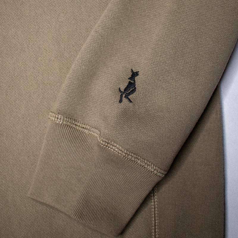 Close-up of an olive green sweatshirt with a small embroidered logo on the chest.